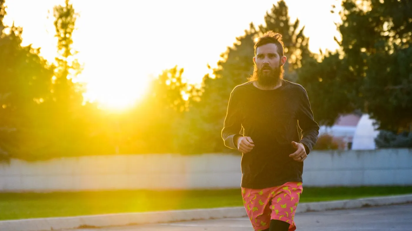 Hombre con barba trotando por una calle al amanecer, con el sol de frente: imagen para la guía de pastillas para la erección y rutina diaria